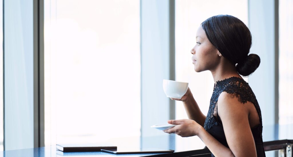 Business woman holding a cup of coffee and looking thoughtfully out a window
