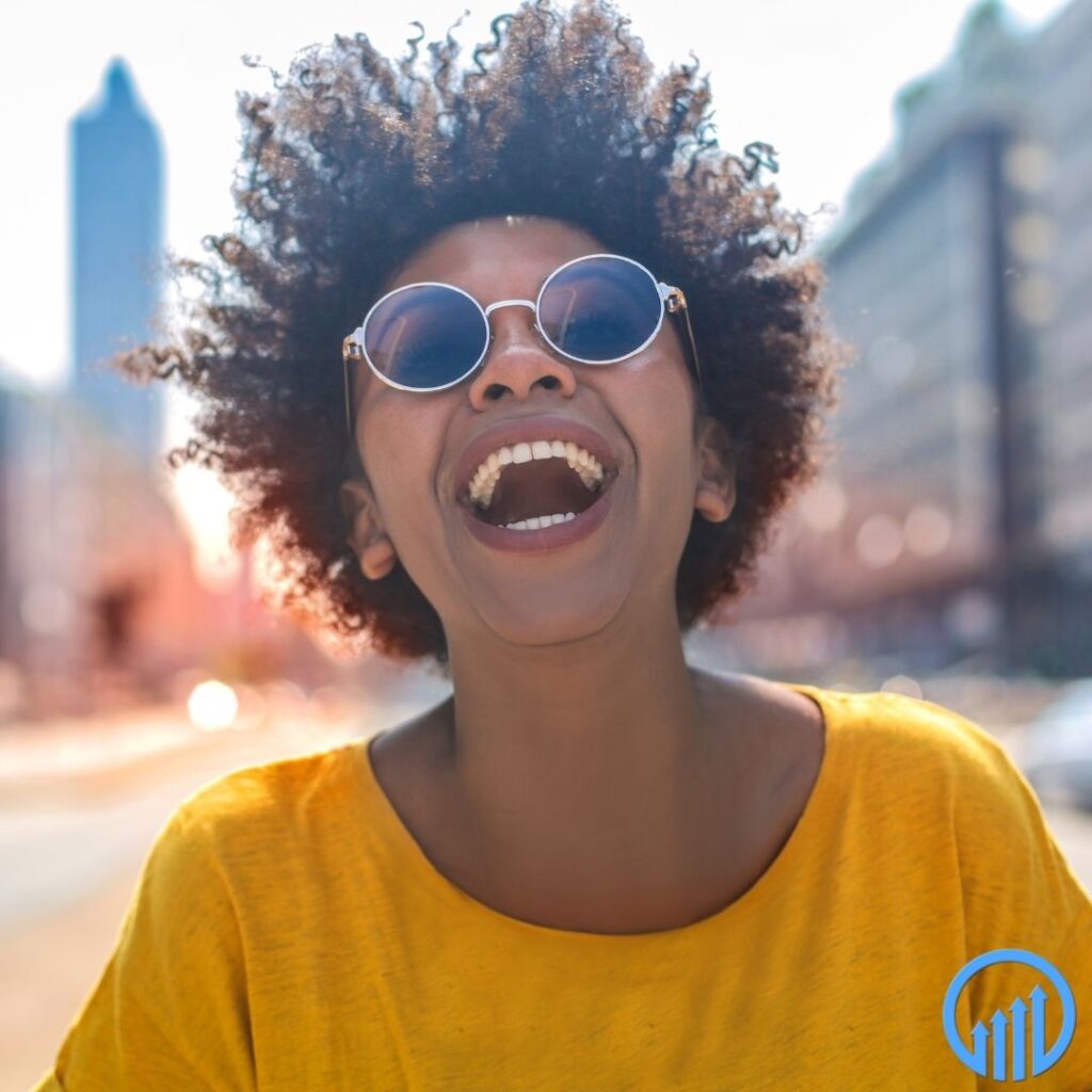 happy African American woman in a yellow shirt and round sunglasses laughing