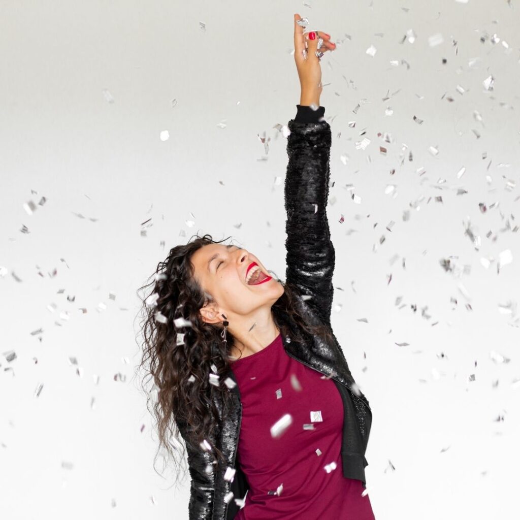 Smiling woman celebrating with confetti